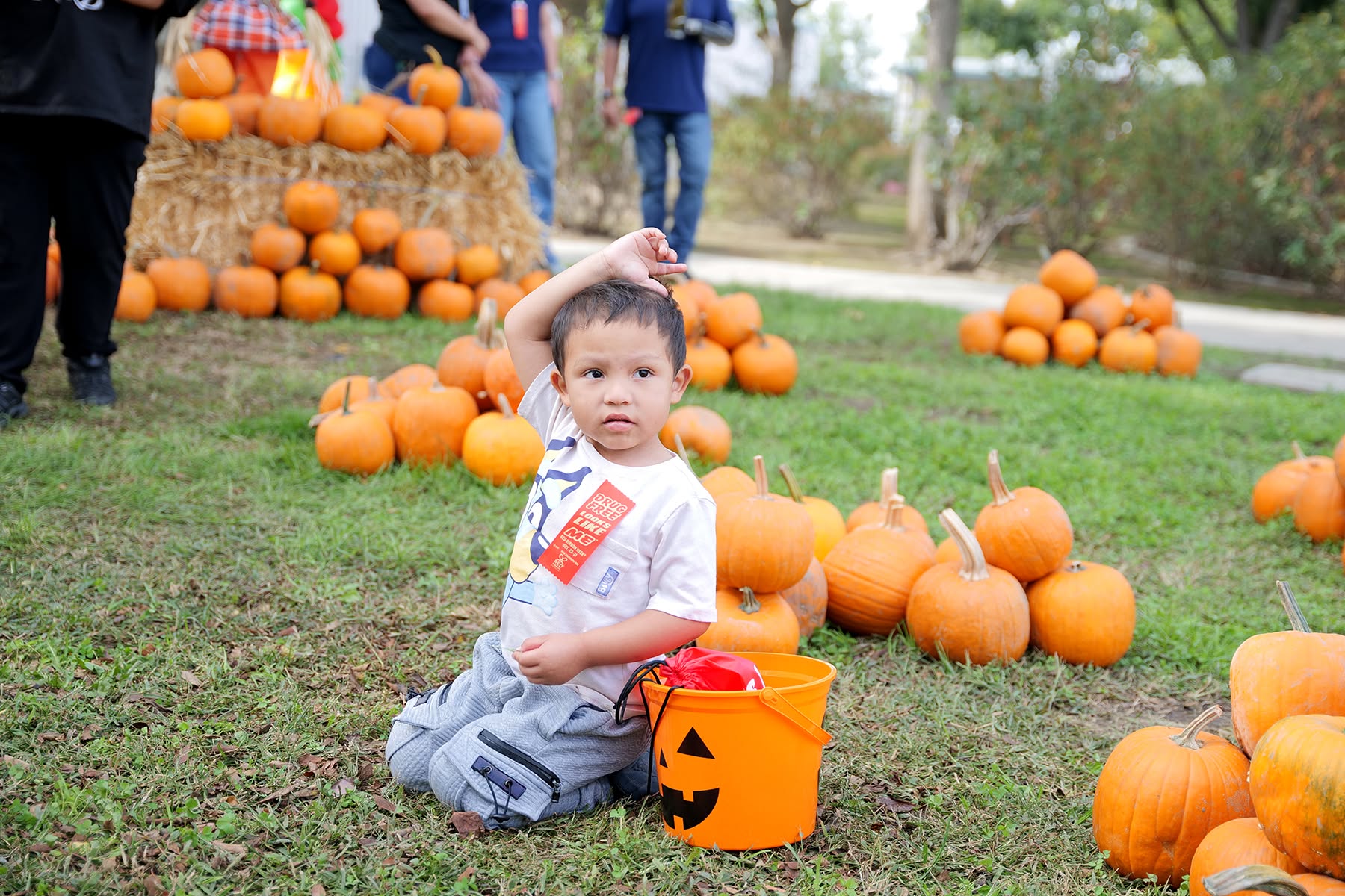 4 Student sitting in pumpkin patch with a bucket of candy.